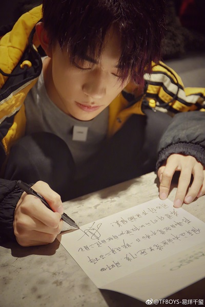 低頭寫字的易烊千璽。(取自新浪微博@TFBOYS-易烊千璽)