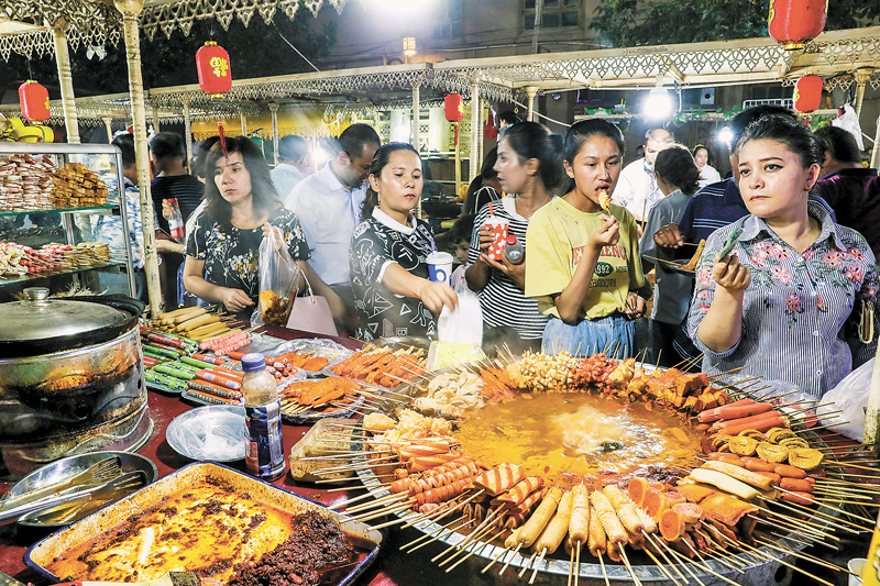新疆喀什老城夜市上,幾位當地居民在麻辣燙攤前品嘗美食。(新華社資料照片)